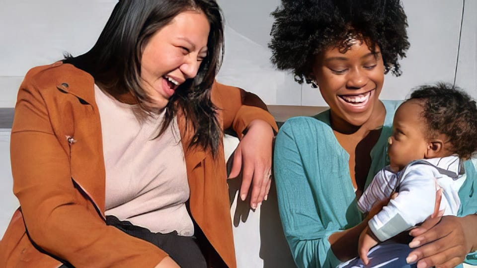 Parents affectionately holding small child on shoulders
